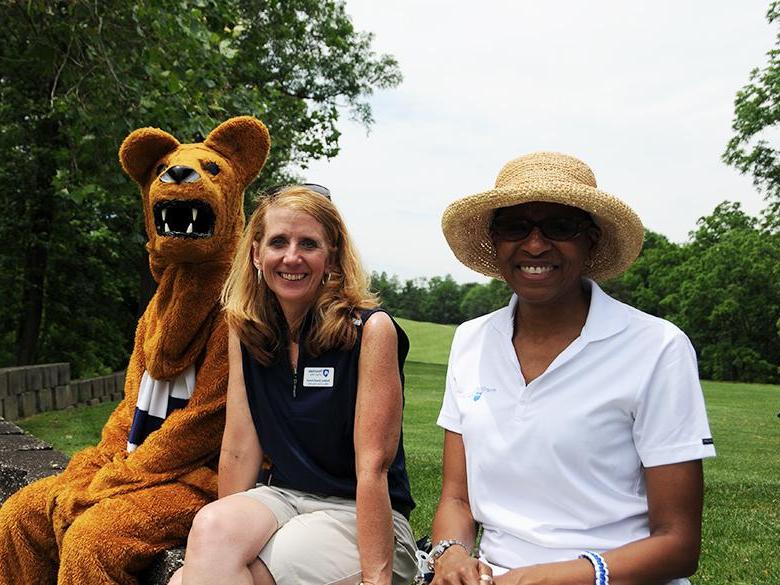 two staff members posing together with the nittany lion mascot